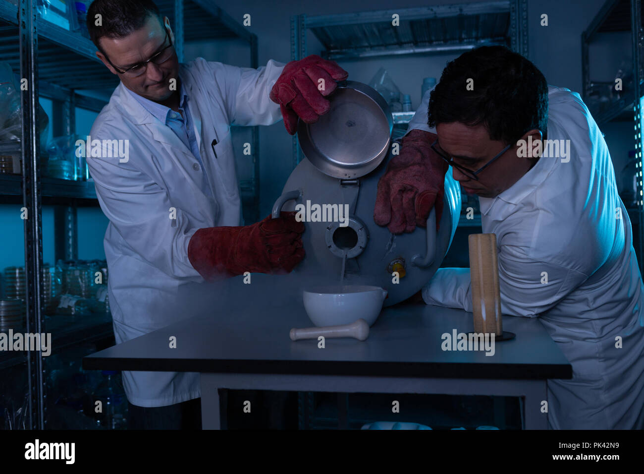 Gli scienziati maschio versando il liquido in un recipiente Foto Stock