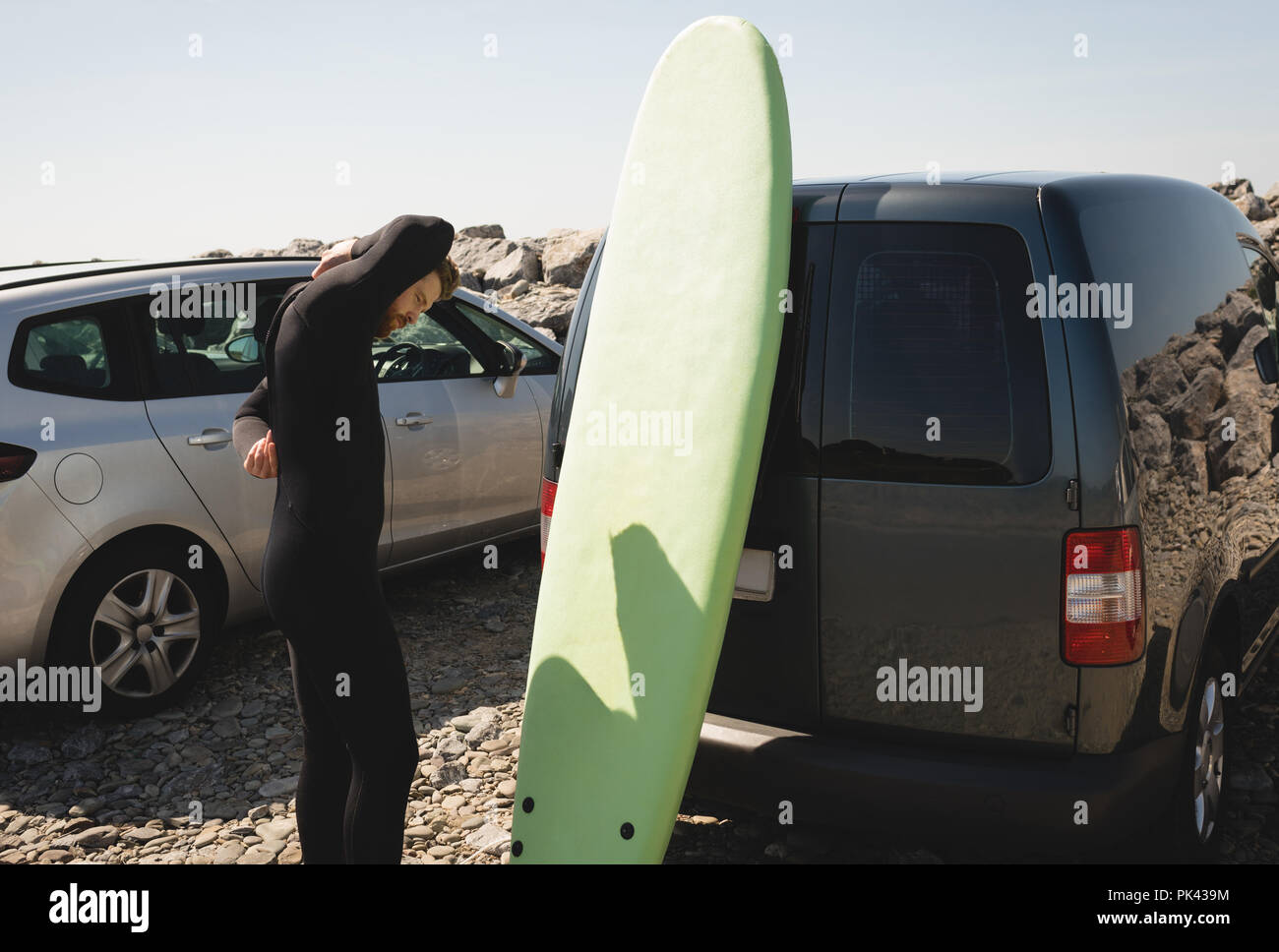 Surfer muta da indossare vicino alla spiaggia Foto Stock