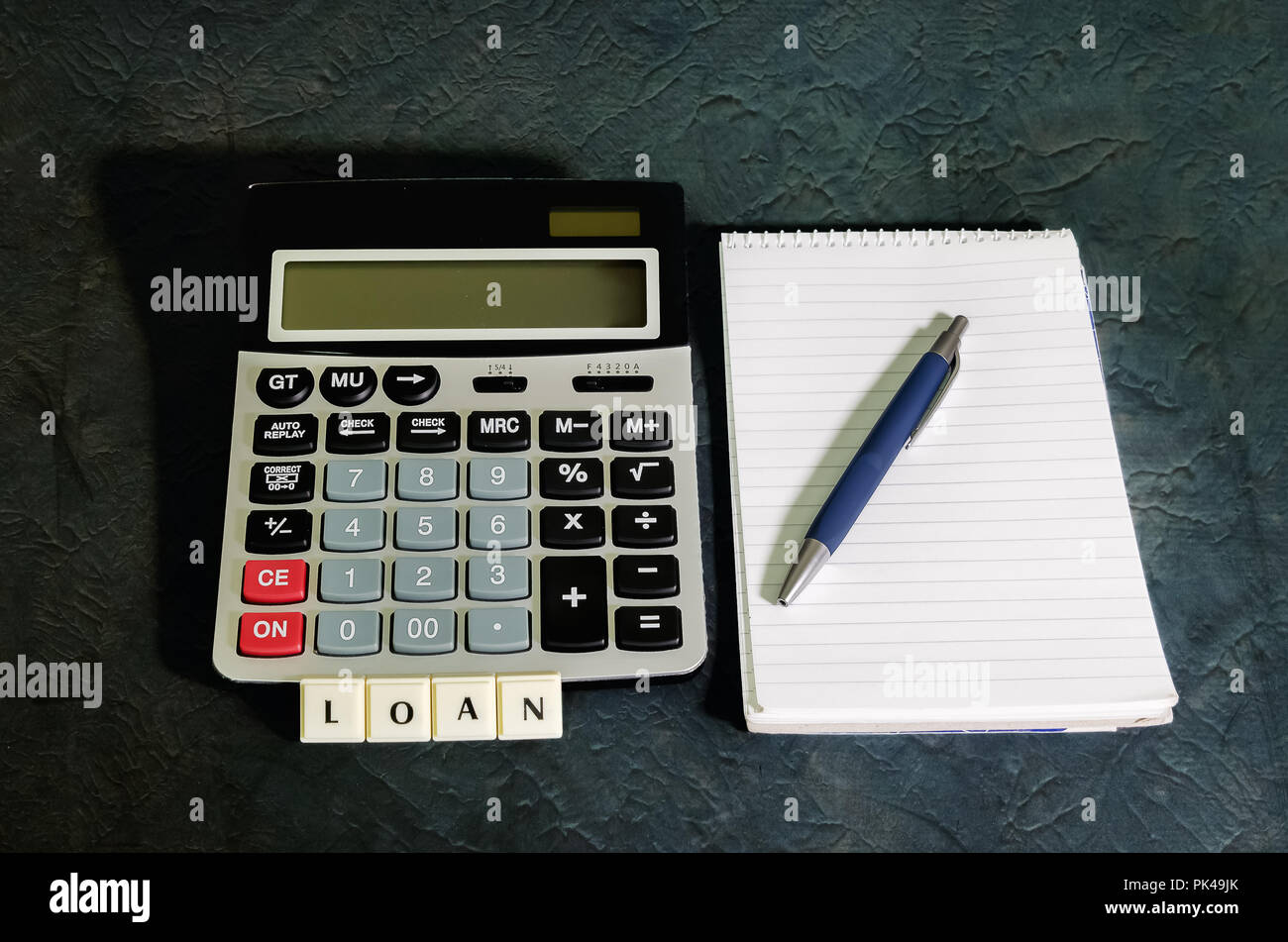 Il concetto di prestito, una calcolatrice accanto al notebook a spirale con la penna Foto Stock