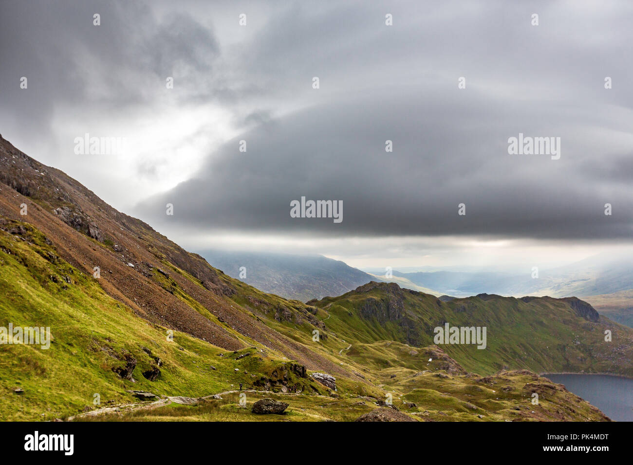Le splendide vedute guardando fuori attraverso la campagna del Welsh come ho salito Mount Snowdon. La Moody nuvole aggiunto al suggestivo paesaggio. Foto Stock