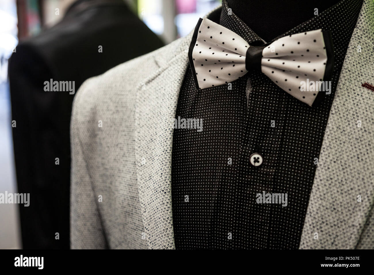 Cravatta a farfalla bianca con punti neri, sul display con una camicia nera e una lana bianca tuta giacca. Cravatte sono un simbolo di eleganza e stile, attualmente indietro Foto Stock