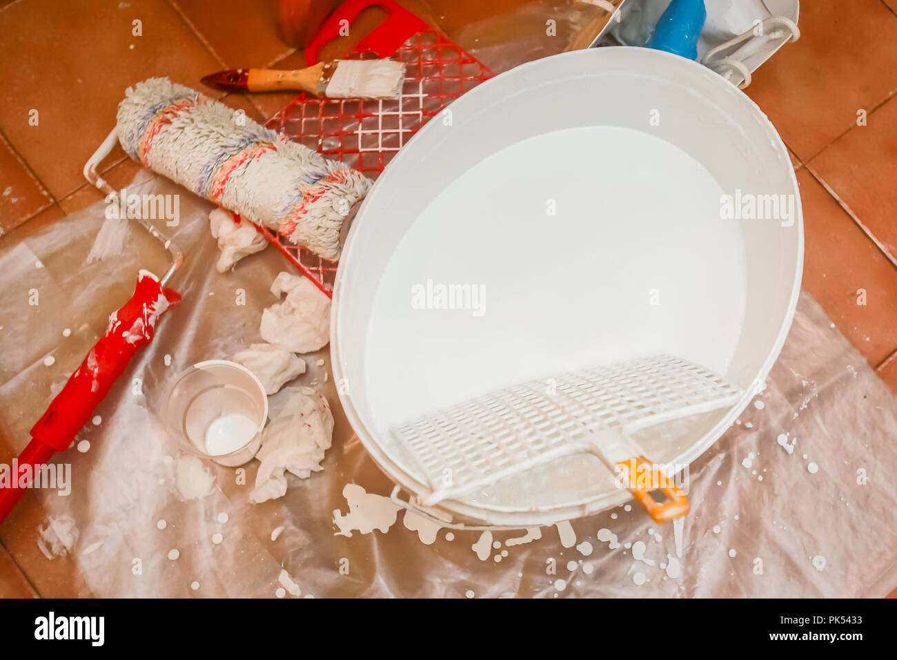Benna con il colore bianco e gli strumenti per la pittura pronta per la verniciatura di una parete di un appartamento. Foto Stock