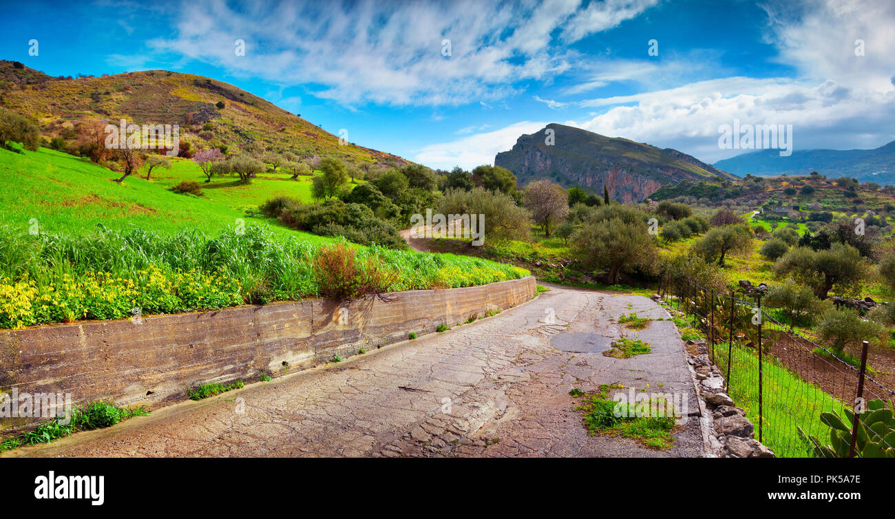 La vecchia strada intorno al lago Rosamarina, Sicilia, Italia, Europa. La molla giornata soleggiata tra la fioritura dei giardini. Foto Stock