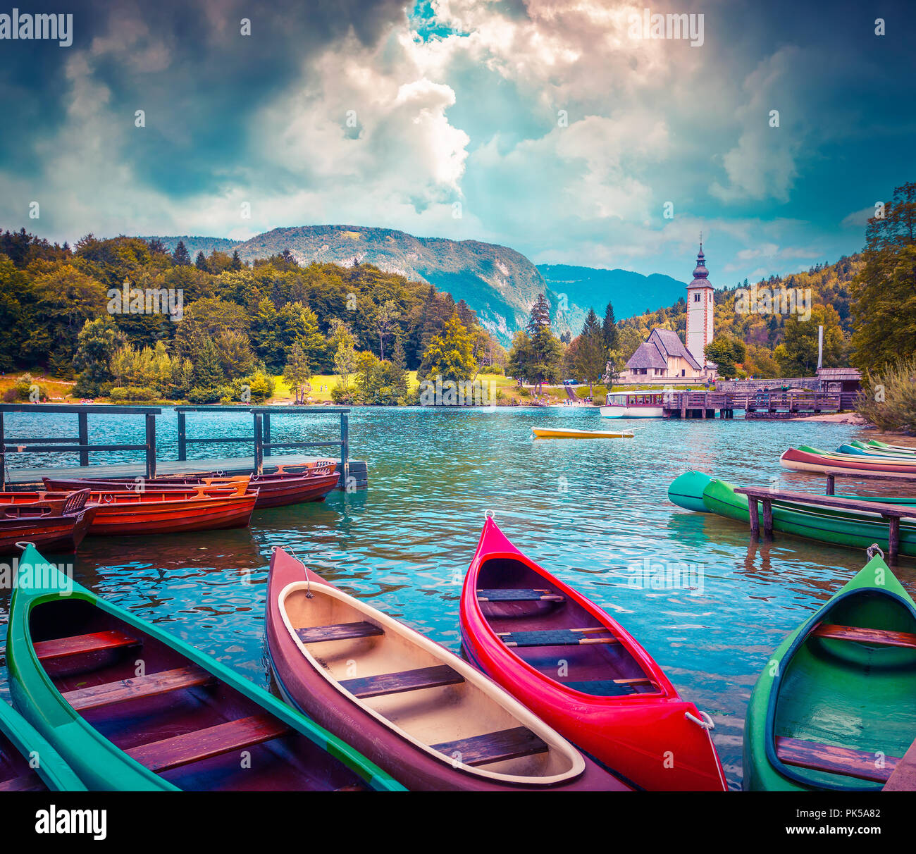 Il lago di Bohinj con barche e Chiesa di San Giovanni Battista, il Parco Nazionale del Triglav, sulle Alpi Giulie, Slovenia. Instagram tonificante. Foto Stock