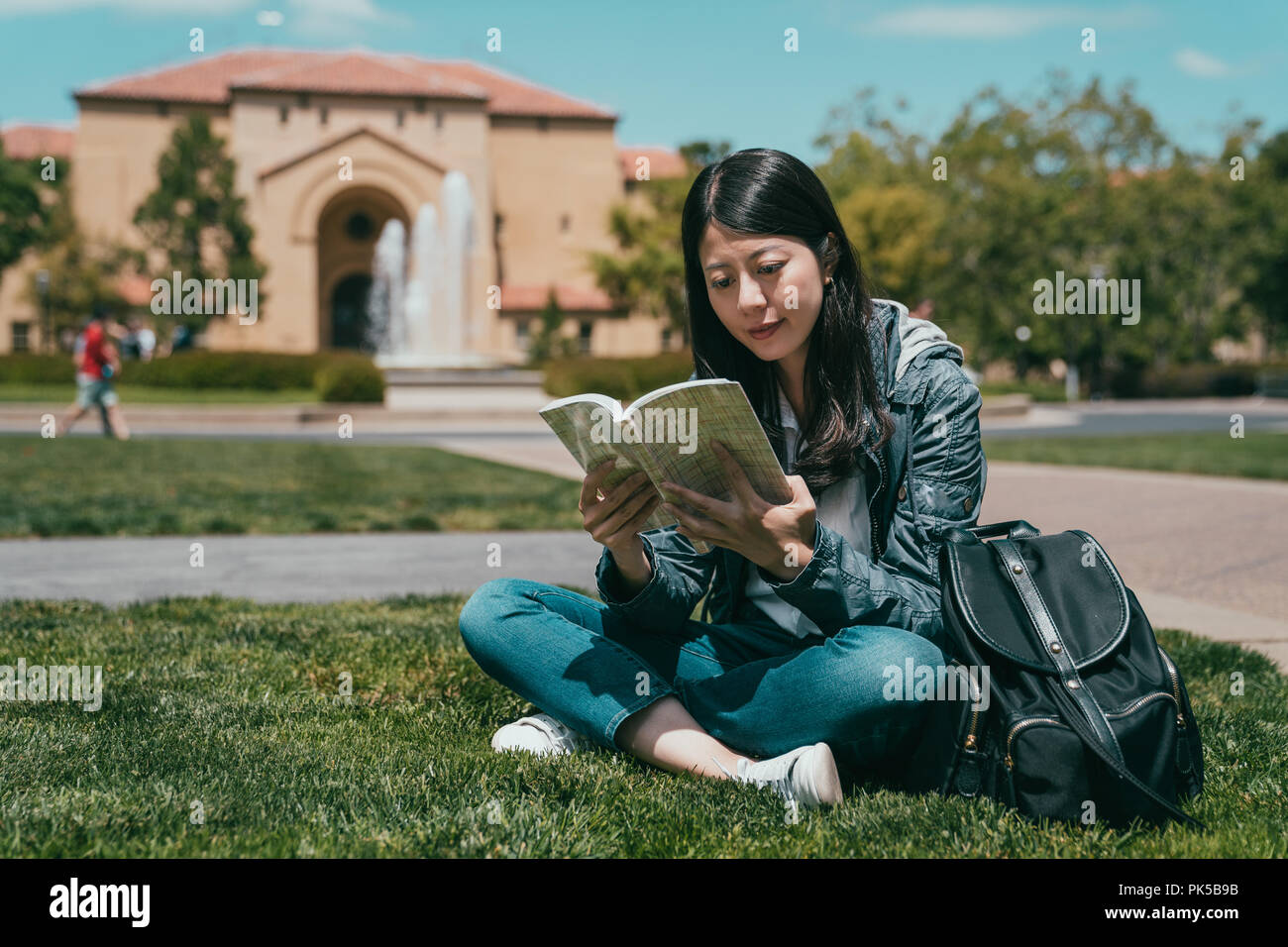 Giovani donne lo scambio di studenti seduti a terra e la lettura del suo libro preferito dopo la classe. Foto Stock