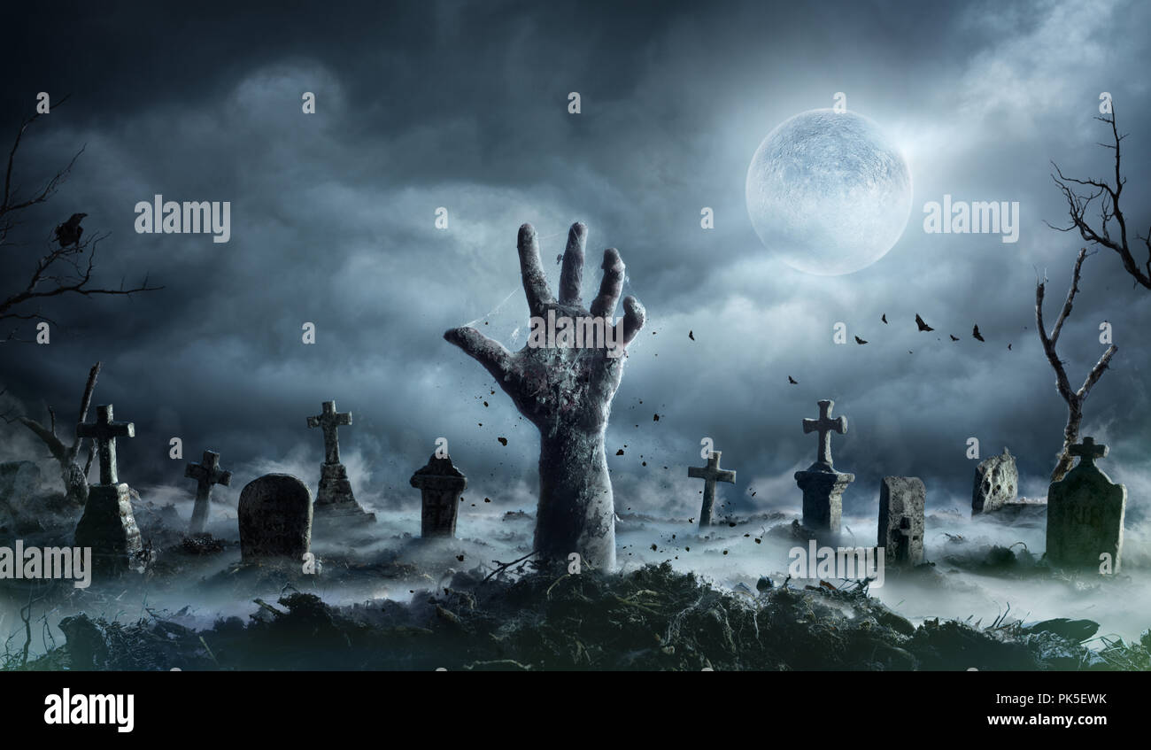 Mano di zombie che aumenta di un cimitero di notte spooky Foto Stock