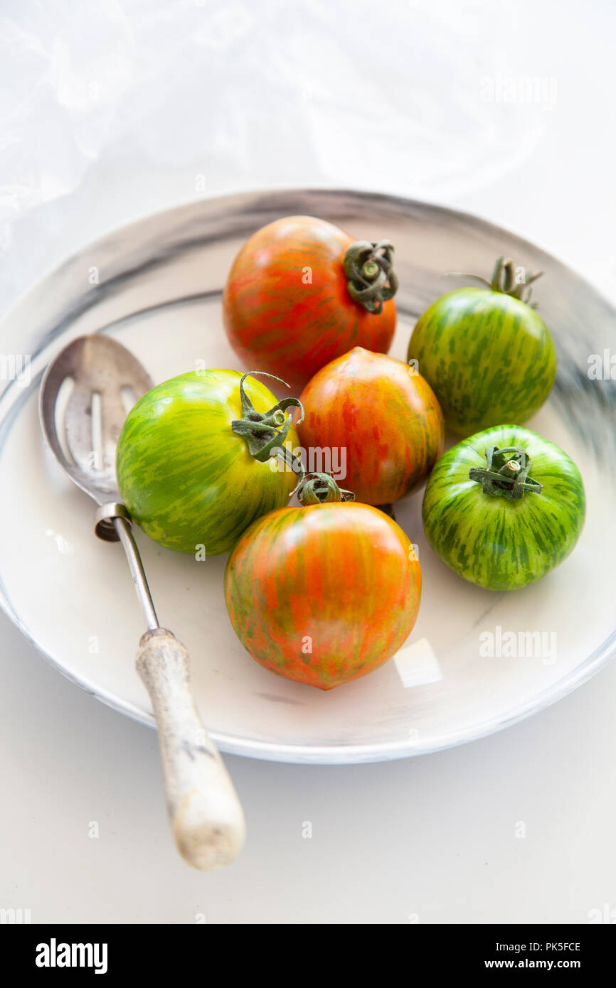 Cimelio di freschi pomodori in un bianco e grigio ciotola in marmo su sfondo bianco Foto Stock