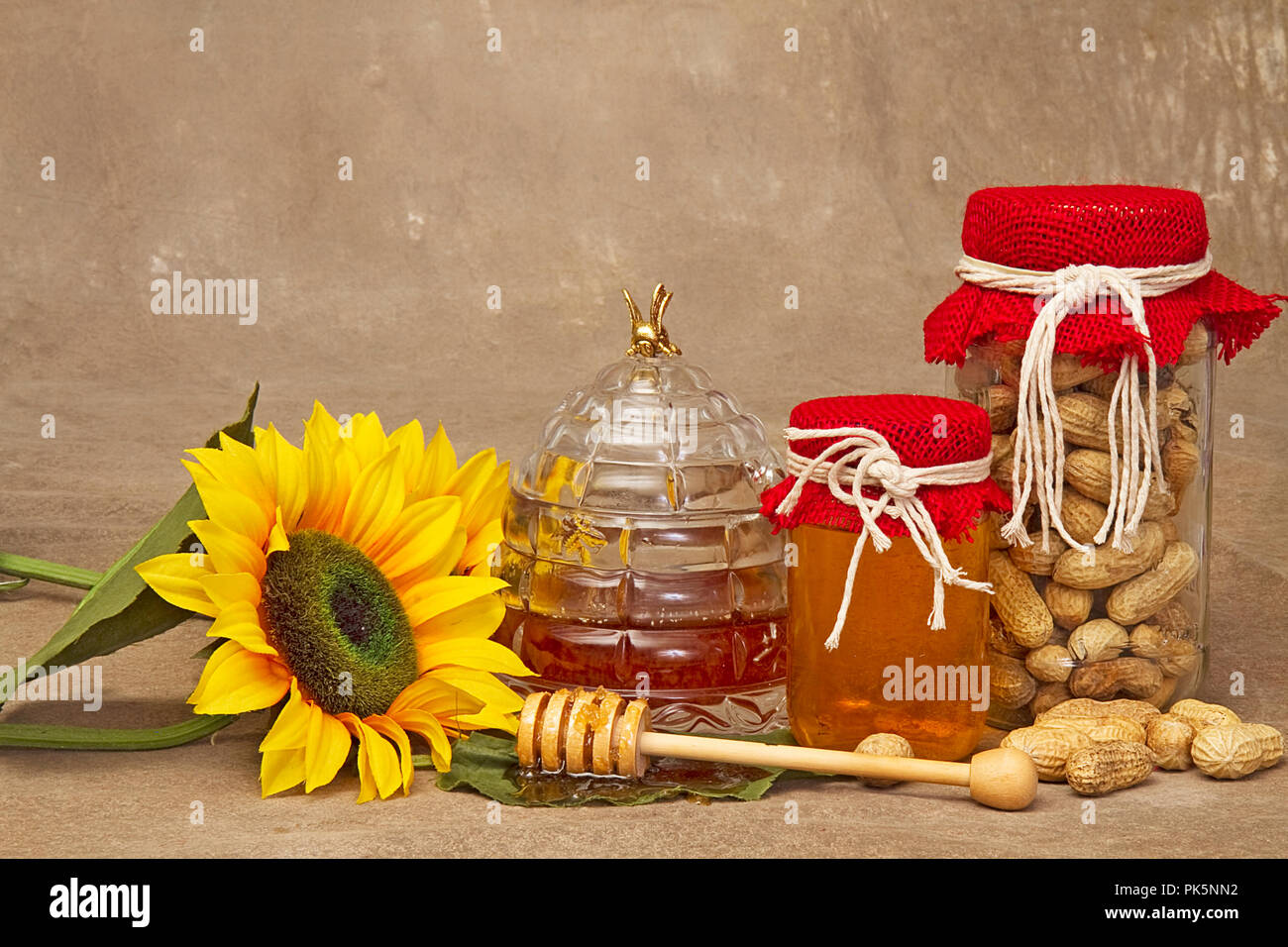 Paese di immagini su sfondo marrone comprendente un vasetto di arachidi e di alcuni con il miele. Girasoli appoggiato accanto a prodotti alimentari. Foto Stock