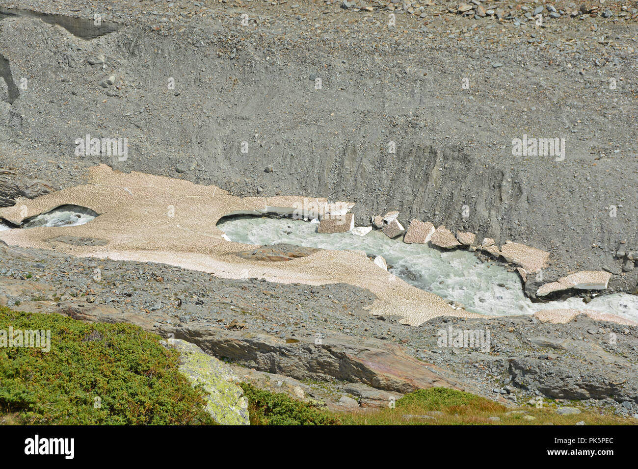 Un ghiacciaio tagli di flusso attraverso vecchi ponti di neve in montagna. In alto a sinistra parti del ghiacciaio può essere visto Foto Stock