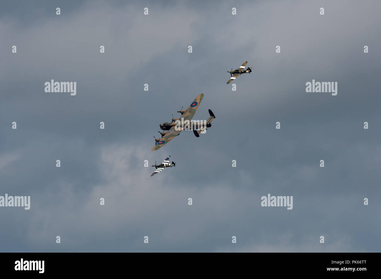 Lancaster PA474 del Battle of Britain Memorial volo con disegni Spitfire ed Hurricane banking contro un cielo pesante Foto Stock