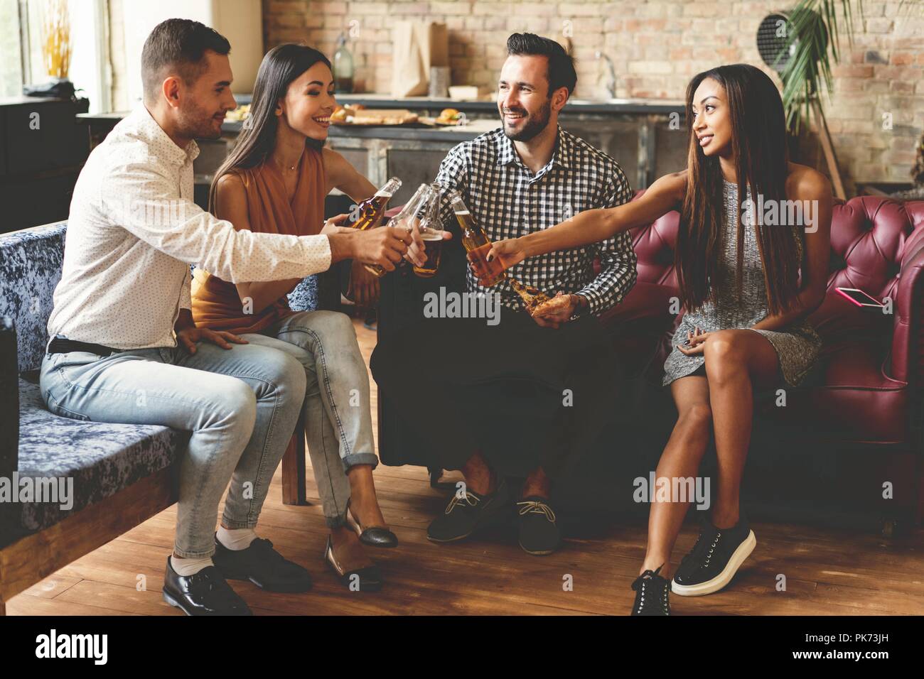 Trascorrere molto tempo con i migliori amici. Il gruppo di allegro giovani gustando cibi e bevande mentre trascorrere del tempo piacevole nel confortevole sedie sulla cucina insieme. Foto Stock