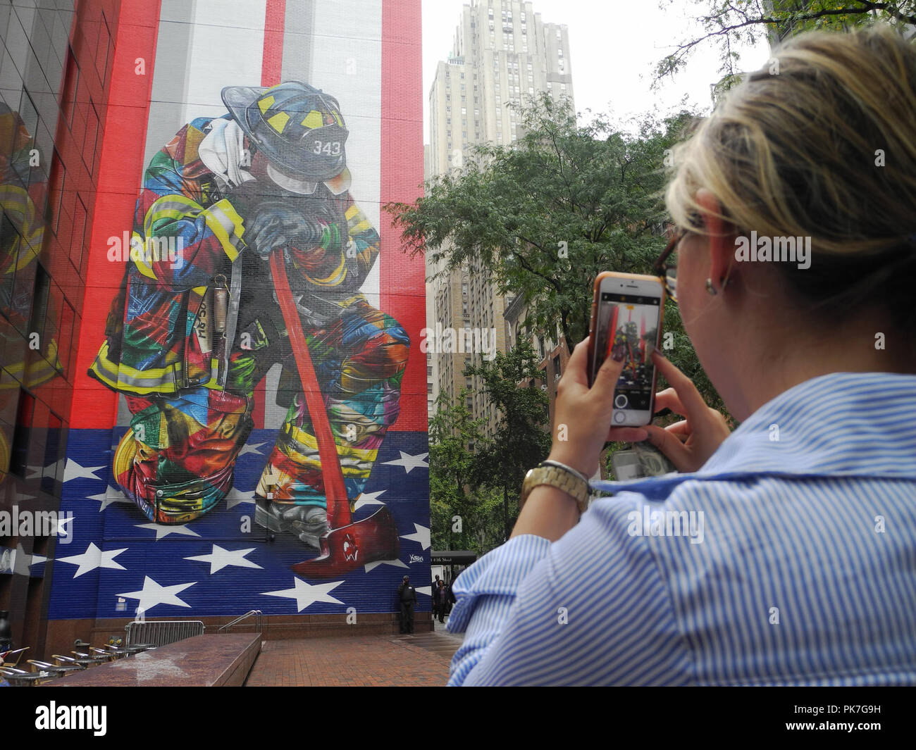 New York, Stati Uniti d'America. Undicesimo Sep, 2018. Una donna fotografie murale " il Braves di 9/11' dall artista brasiliano Eduardo Kobra. 17 anni dopo gli attentati terroristici di settembre 11, 2001, un artista di New York ha presentato il suo murale di un vigile del fuoco in lutto. Credito: Johannes Schmitt-Tegge/dpa/Alamy Live News Foto Stock