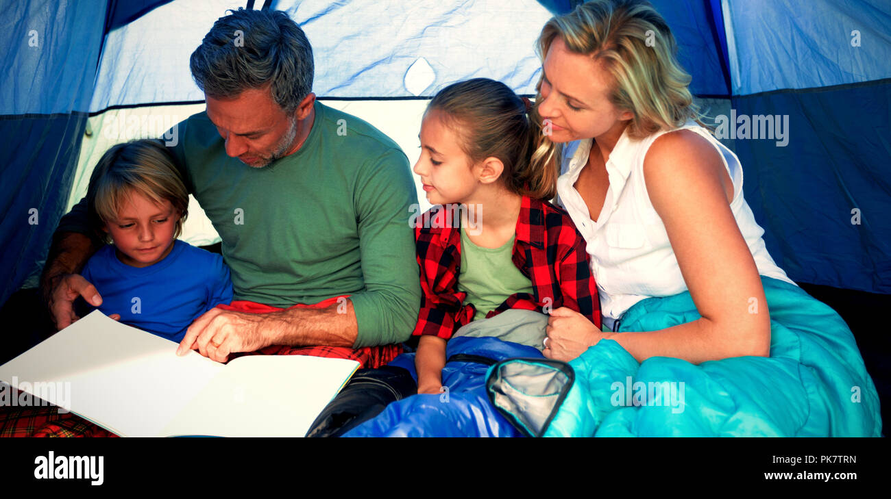 Famiglia libro di lettura nella tenda Foto Stock