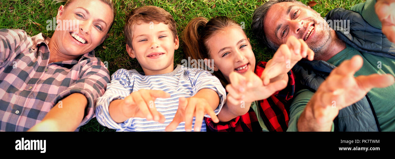 La famiglia felice sdraiati sull'erba e compiendo gesti con le mani Foto Stock