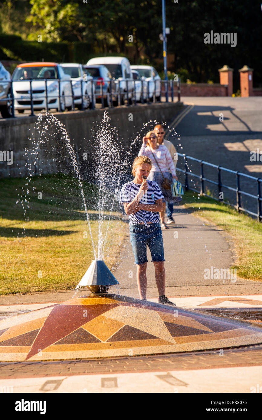 Regno Unito, Inghilterra, Yorkshire, Filey, il lungomare, il bambino a mangiare il gelato accanto a punti della bussola fontana Foto Stock