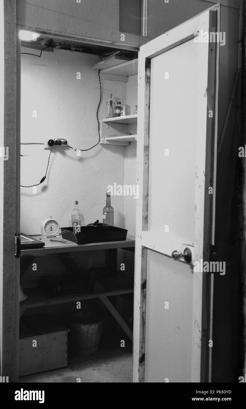 Degli anni Cinquanta, storico, una porta aperta per una riproduzione fotografica camera oscura in cui una pellicola fotografica è sviluppato e dove un vassoio di sviluppo in cui la striscia di film è inserito e miscelato con sostanze chimiche può essere visto. Foto Stock
