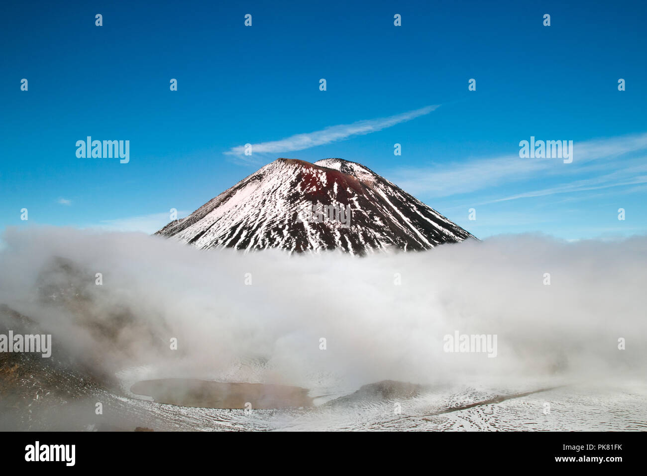 Il picco del vulcano attivo sopra le nuvole nel cielo, bellissime innevate montagne vulcaniche con la cima del monte Ngauruhoe, Nuova Zelanda Foto Stock