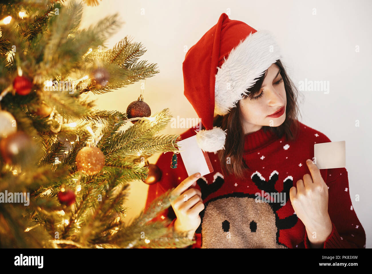 Shopping di Natale e vendite. bellissima ragazza con due carte di credito per uno sconto e acquisto di regali su sfondo di golden albero di natale con luci Foto Stock