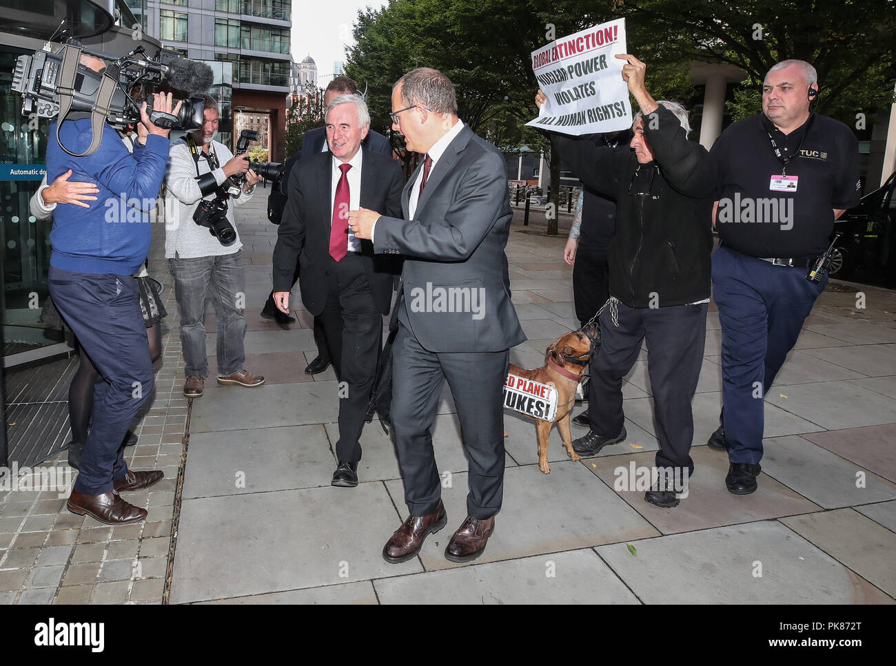 Cancelliere ombra John McDonnell (cravatta rossa) incontra un anti-nucleare attivista e il suo cane come egli arriva a parlare al Congresso TUC in Manchester. Foto Stock