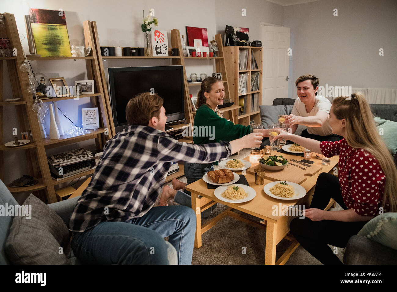 Due coppie sono avente una sera a cena a casa e sono la tostatura le loro bevande prima di mangiare. Foto Stock