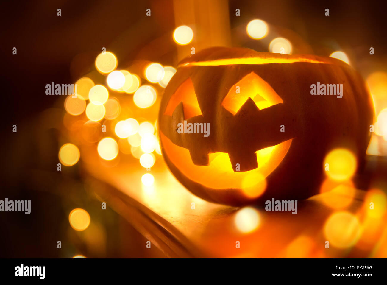 Un allegro sorridente Jack O Lanterna di halloween collocato su un caminetto con le luci fairy Foto Stock