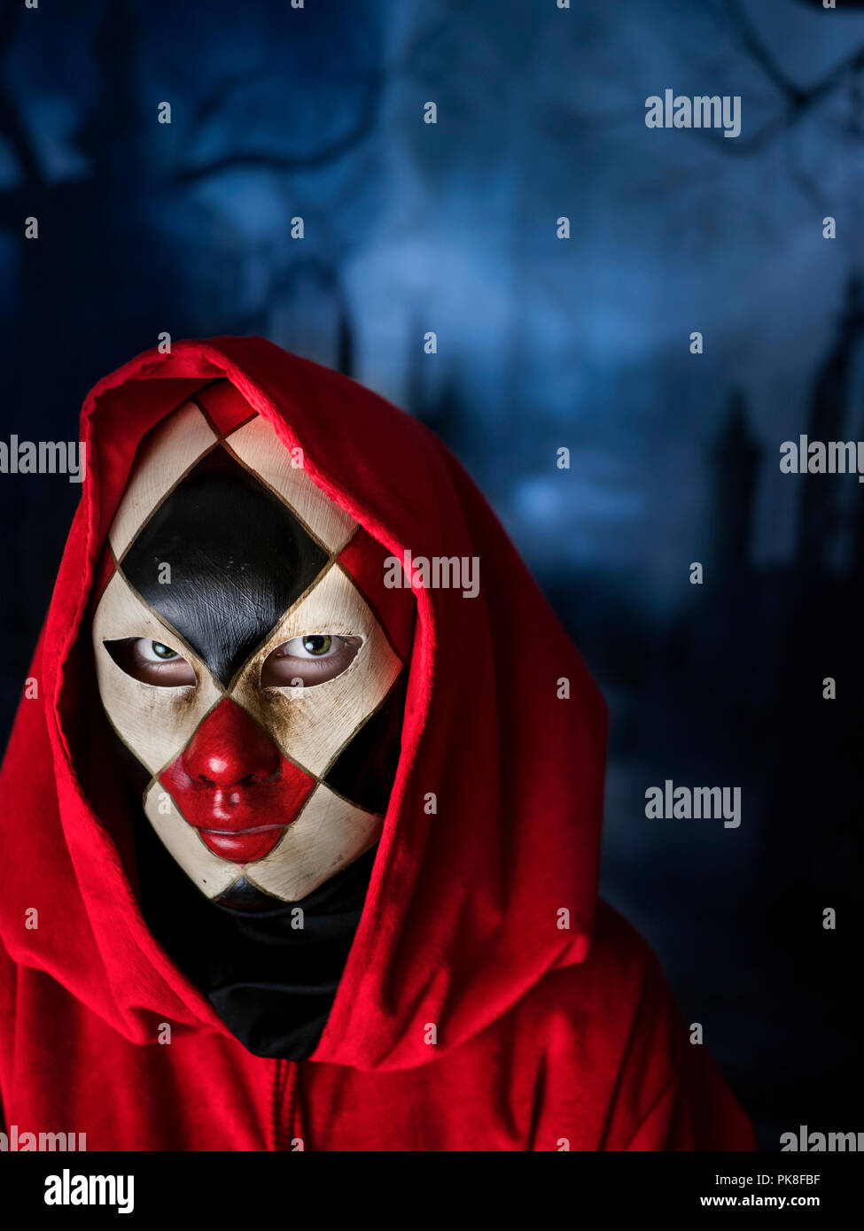 Donna mascherata in un cimitero scuro, veneziana verificato piena maschera blu scuro notte di Halloween di carnevale Foto Stock