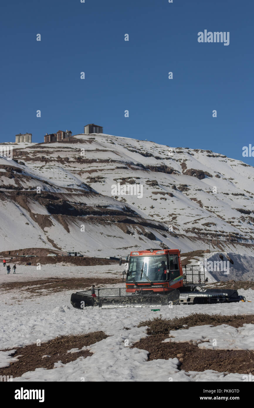 La Caterpillar Tractor per pulire il parcheggio di neve in montagna sul retro Valle Nevado Ski Resort, intorno ad alcune persone piace la montagna innevata Foto Stock