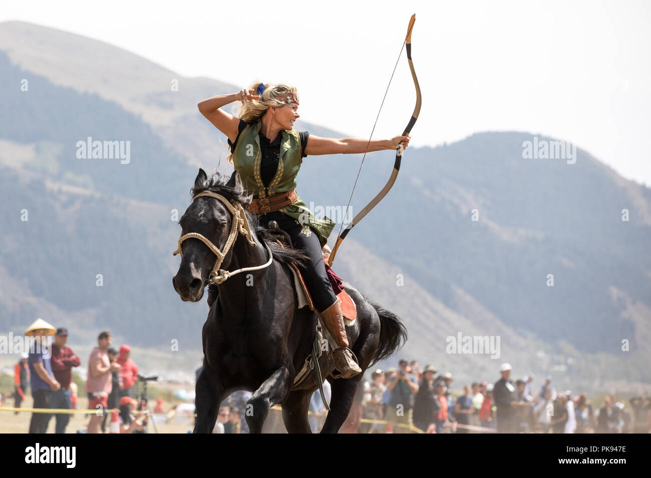 Città Cholpon-Ata, Kirghizistan - Settembre 6, 2018: Femmina archer mirando a un bersaglio durante un tradizionale cavallo tiro con l'arco della concorrenza. Foto Stock