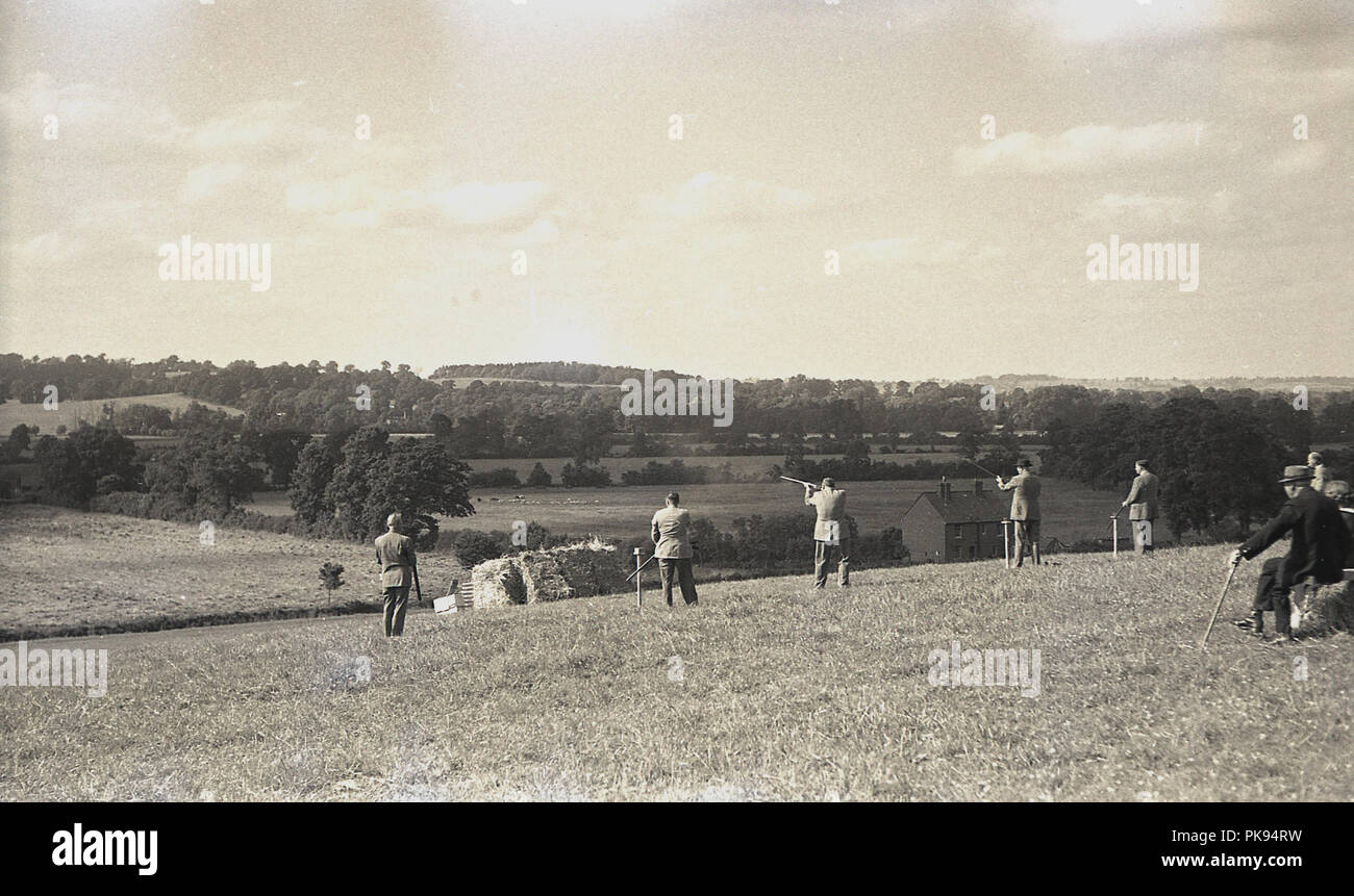 1930s, storico paese rurale inseguimenti, colleghi in abbigliamento adatto prendendo parte a un tiro sul pendio di una collina, un tradizionale campagna britannica fieldsport. Foto Stock