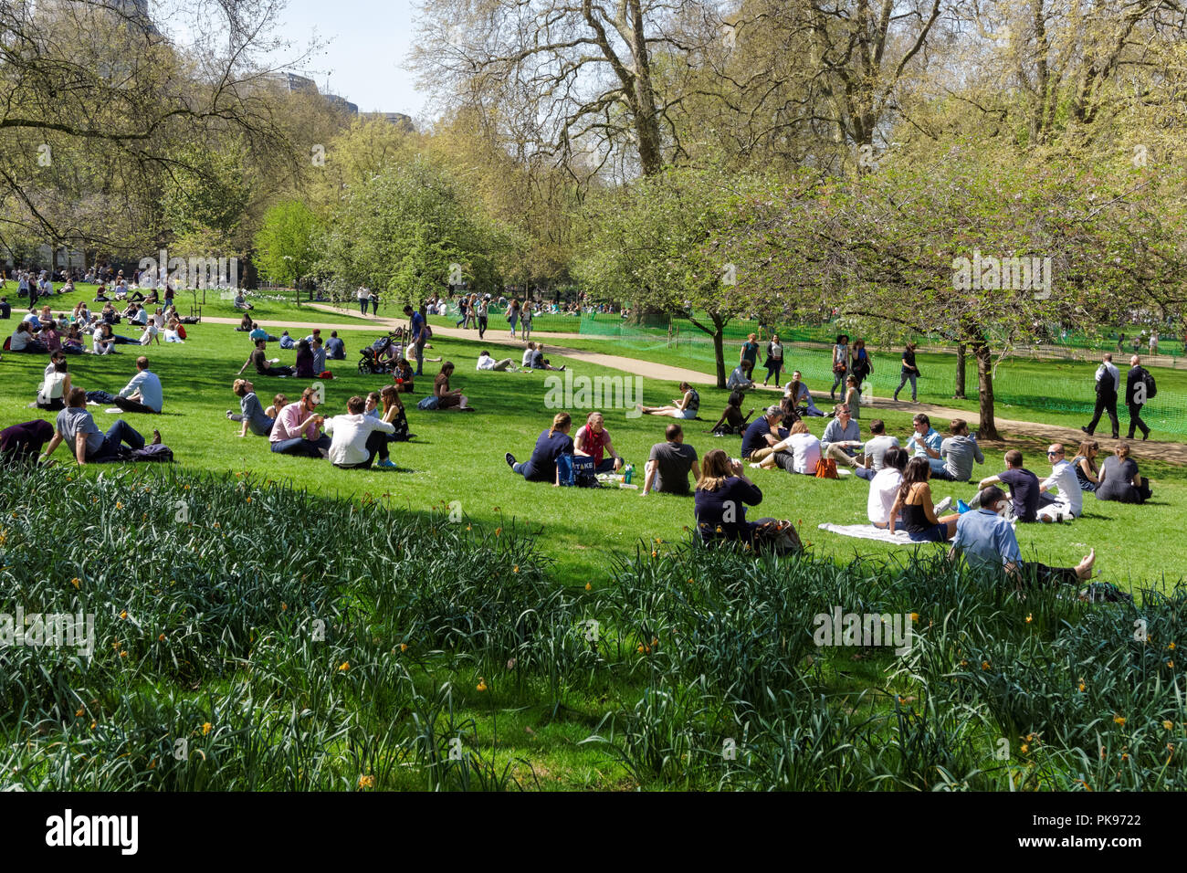 I giovani godono di primavera soleggiata meteo in St James Park. Londra Inghilterra Regno Unito Regno Unito Foto Stock