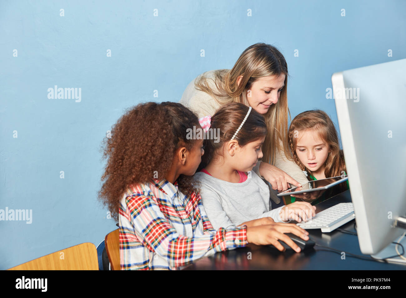 Insegnante aiuta i bambini a computer in computer science insegnamento Scuola elementare Foto Stock