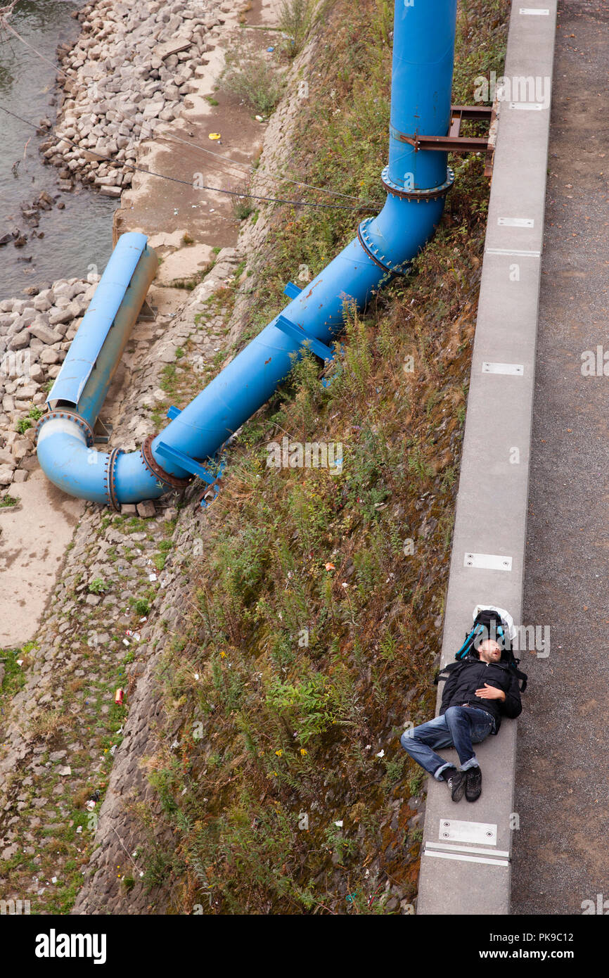 L'uomo assume un pisolino sulla parete sulle rive del fiume Reno nel quartiere Deutz, tubo di fognatura, Colonia, Germania. Mann macht ein Nickerchen auf der M Foto Stock