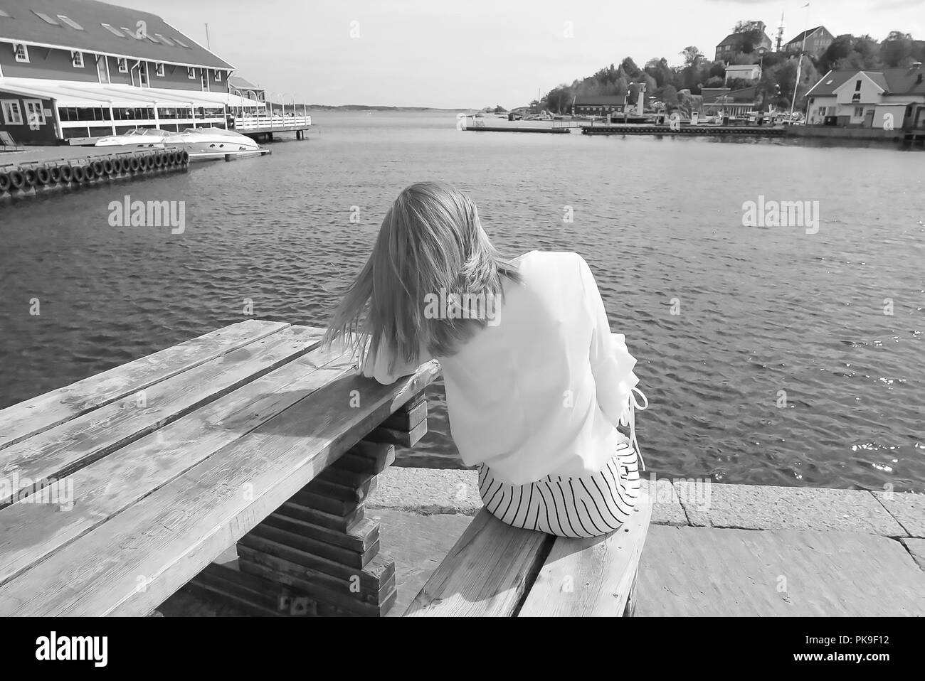 Giovane donna seduta dal Dock Foto Stock