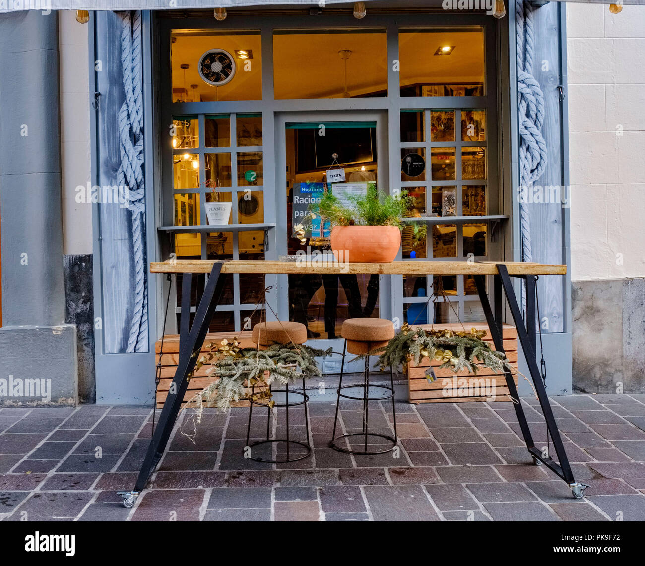 Rustico ferro e tavolo in legno di fronte alla porta di un bar con pentole  sopra e appeso e due sgabelli fatti a mano Foto stock - Alamy