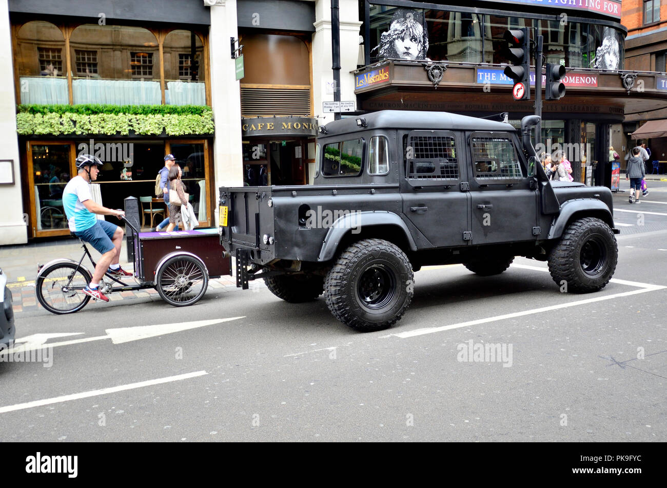 Personalizzato di Land Rover e una bicicletta di consegna nel centro di Londra, Inghilterra, Regno Unito. Foto Stock