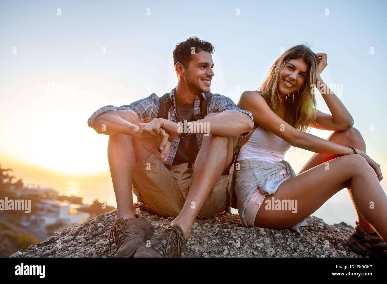 L uomo e la donna gli escursionisti rilassante sulla collina. Escursionista giovane prendendo una pausa seduta su roccia e sorridente. Foto Stock