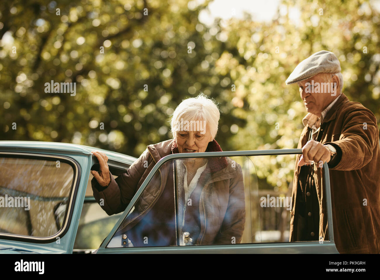 Il vecchio uomo caucasico essendo un gentiluomo e aprire la portiera della macchina per la sua data. La donna come arrivare in auto con l'uomo l'apertura della porta sul giorno d'inverno. Foto Stock