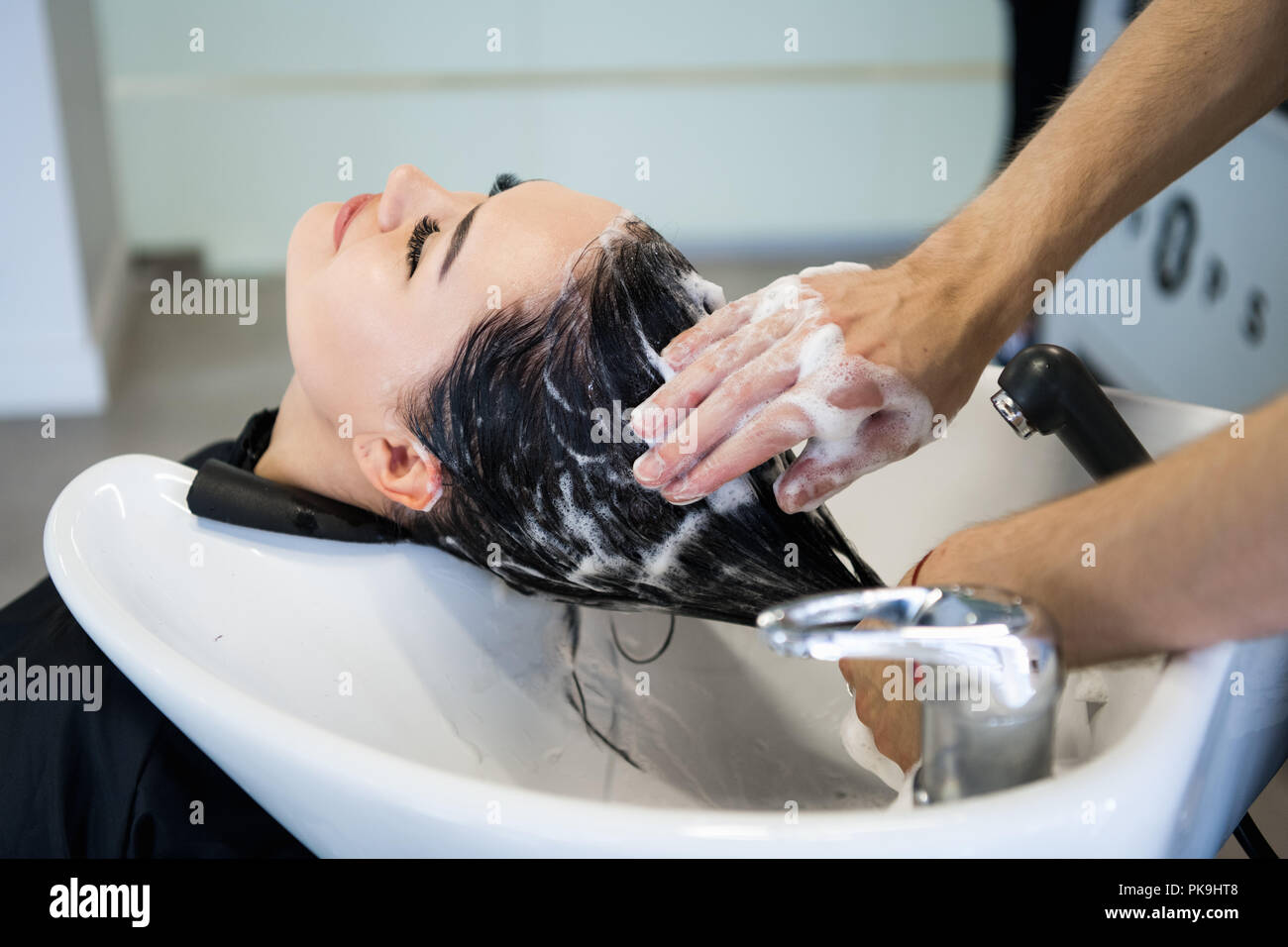 Irriconoscibile parrucchiere professionale capelli di lavaggio per il suo  cliente. Bella parrucchiere capelli di lavaggio per il suo cliente signora  nel salone di parrucchiere. Seduta del client con gli occhi chiusi Foto