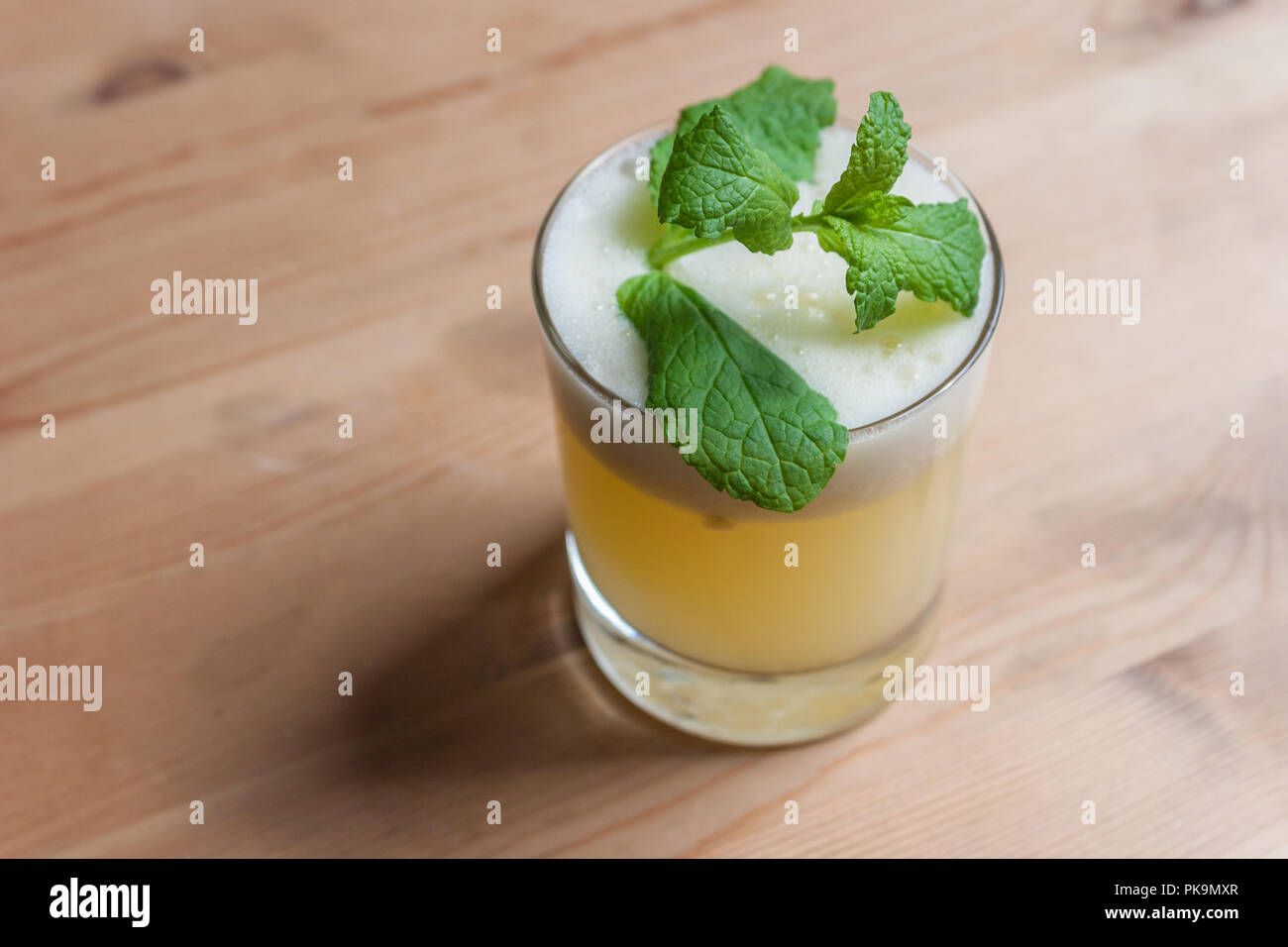 Un fresco cocktail schiumoso o frappè alla menta guarnire su un tavolo di legno o bar. Foto Stock