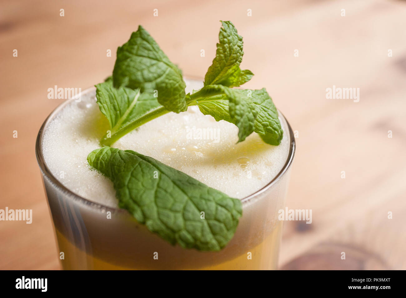 Un fresco cocktail schiumoso o frappè alla menta guarnire su un tavolo di legno o bar. Foto Stock