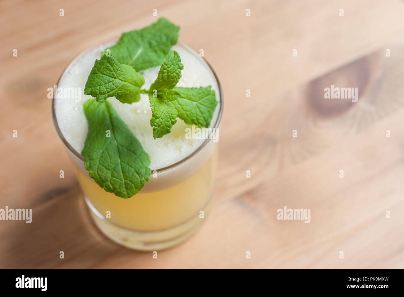 Un fresco cocktail schiumoso o frappè alla menta guarnire su un tavolo di legno o bar. Foto Stock