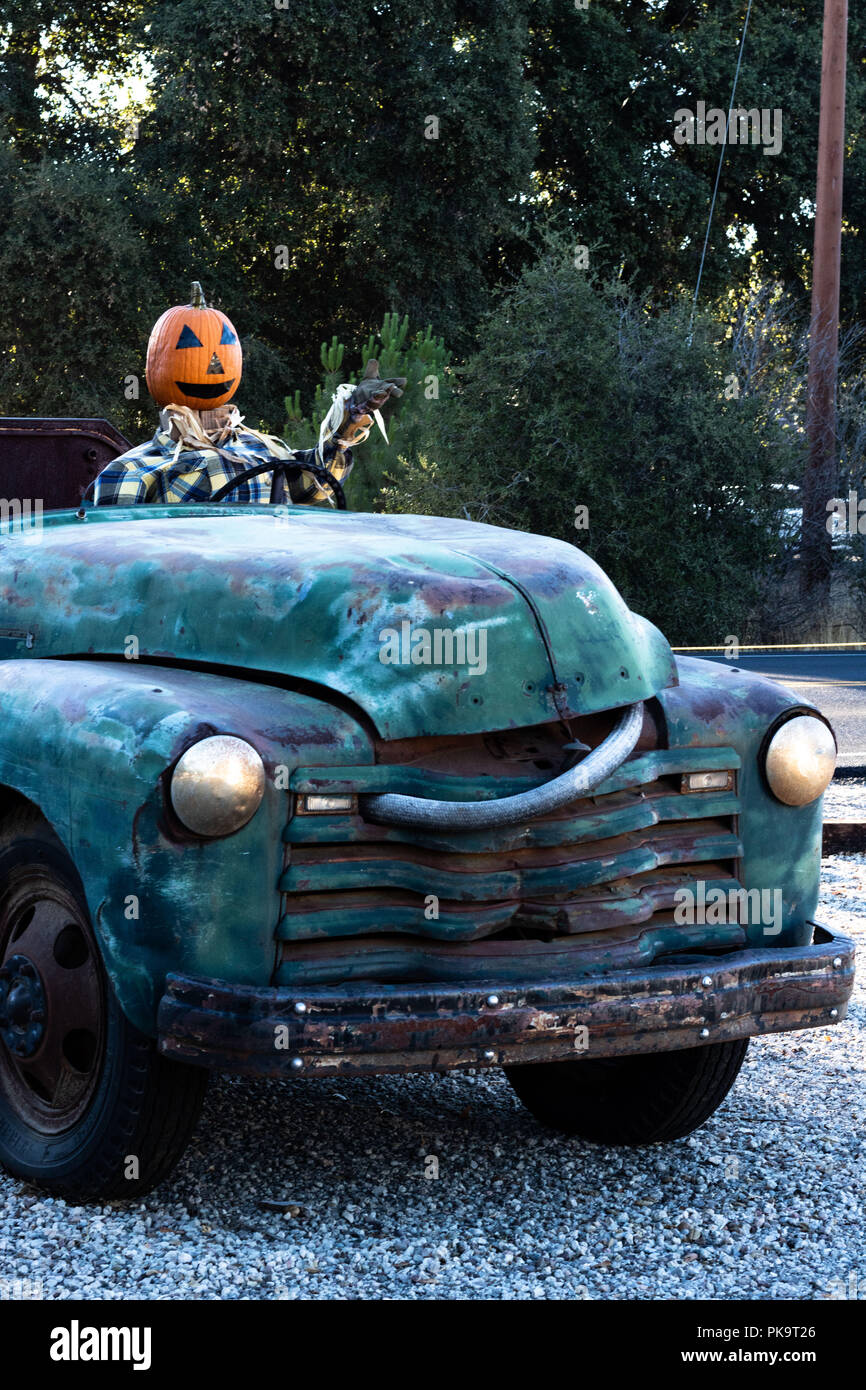 Sorridono felici, accogliente, divertente amichevole testa di zucca spaventapasseri il pilotaggio di un vecchio carrello per un raccolto di Halloween party in autunno Foto Stock