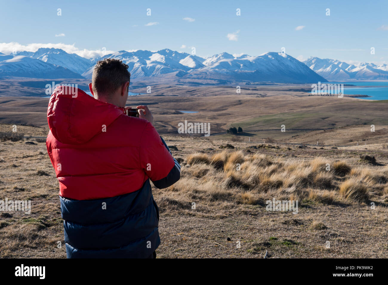Uomo di azione utilizzando la fotocamera di scattare una foto del lago e monti in Nuova Zelanda Foto Stock