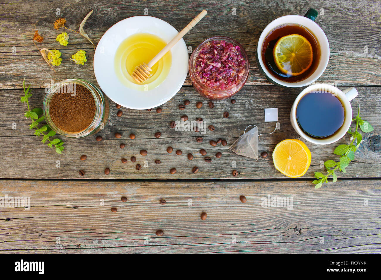 Bollitore per tè e caffè in tazze, cicoria, limone, menta, marmellata fatta di petali di rose, calce secca, miele sul vecchio sfondo di legno. Tonica immagine. Vista dall'alto. Foto Stock