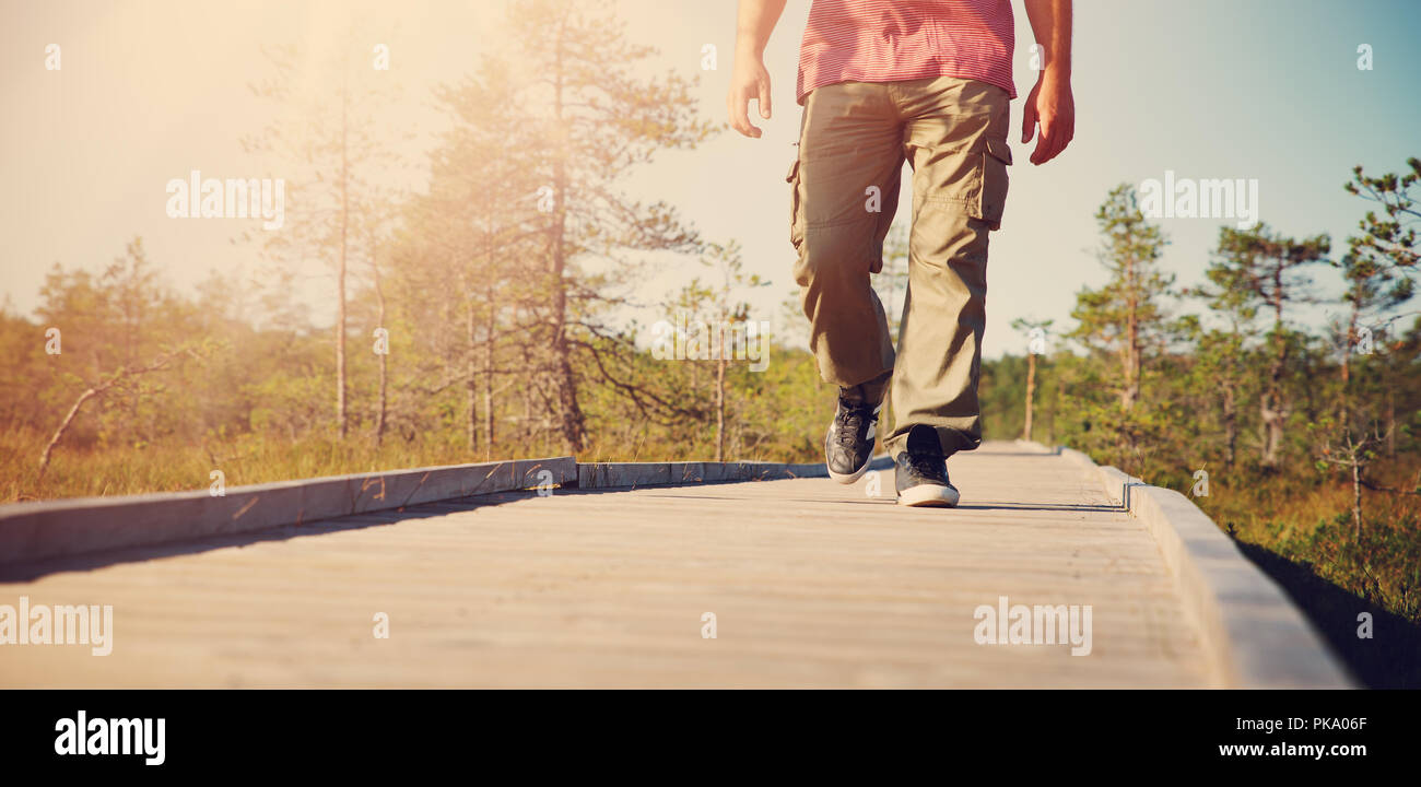 Uomo che cammina sulla passerella di legno in natura Foto Stock