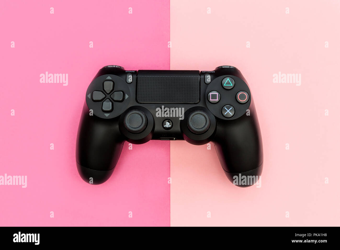 Londra - 05 settembre 2018: videogiochi PlayStation controller di gioco brillante su sfondo rosa Foto Stock