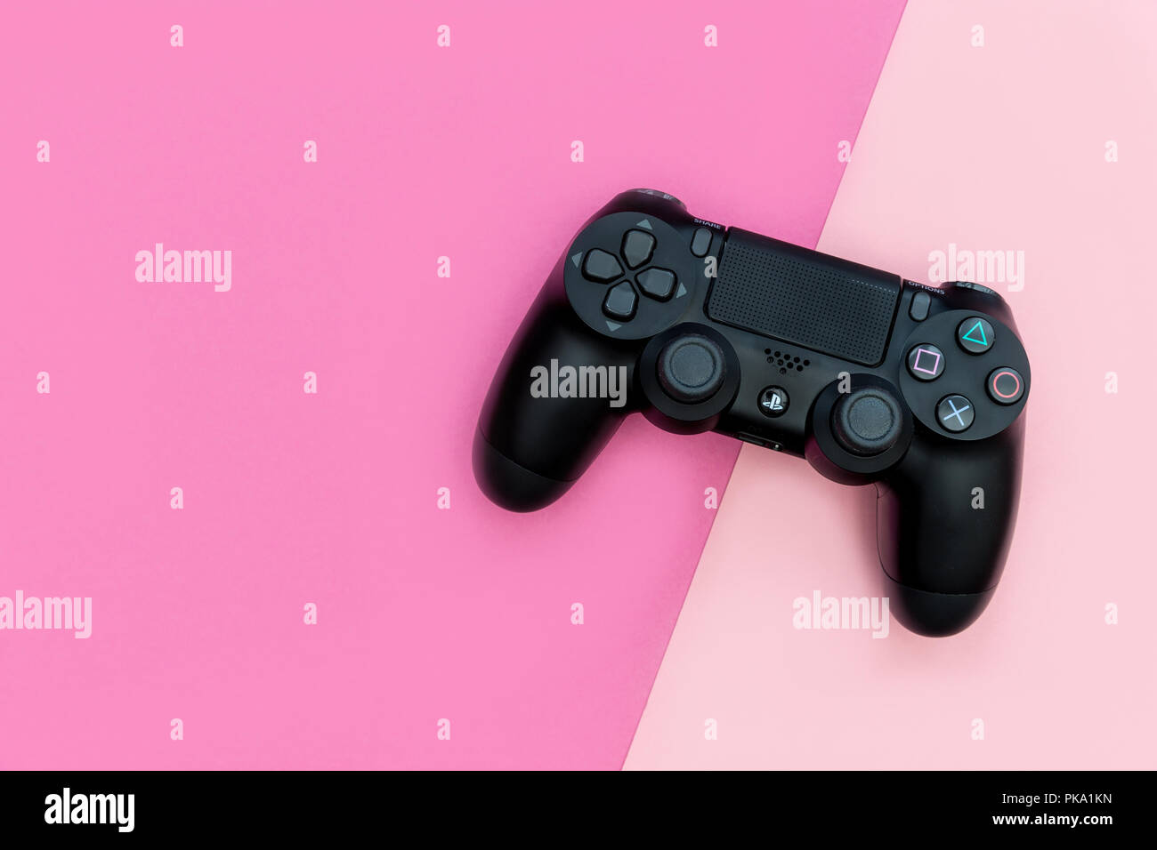 Londra - 05 settembre 2018: videogiochi PlayStation controller di gioco brillante su sfondo rosa Foto Stock