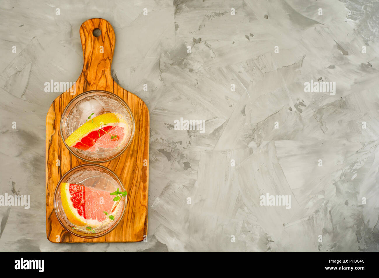 Pompelmo limonata. Due bicchieri di detox bere acqua con succo di pompelmo, rametti di rosmarino e il ghiaccio. Concetto di ricetta, cocktail Foto Stock