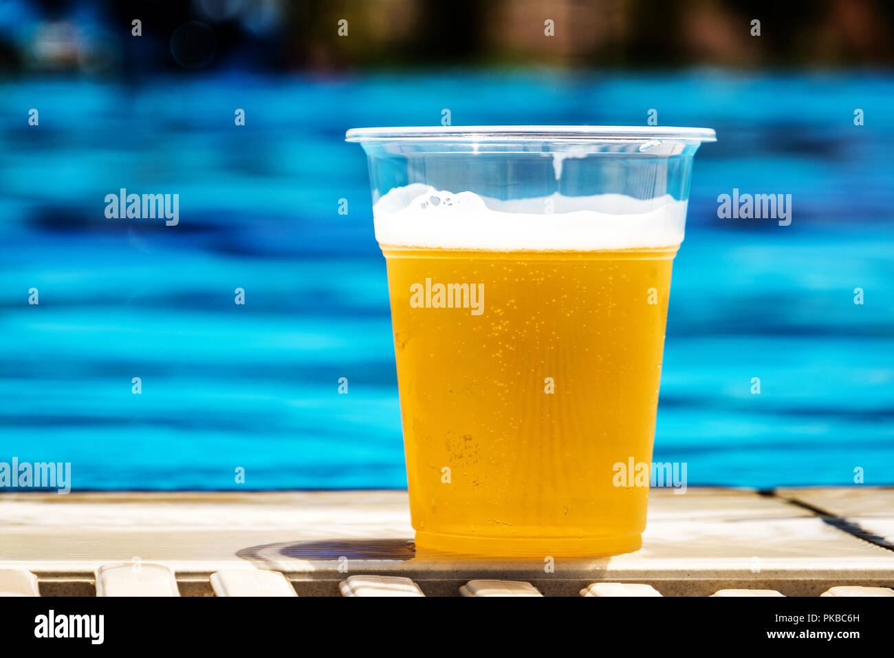 Bottiglia in plastica con birra alla spina nella giornata di sole in estate vicino alla piscina Foto Stock