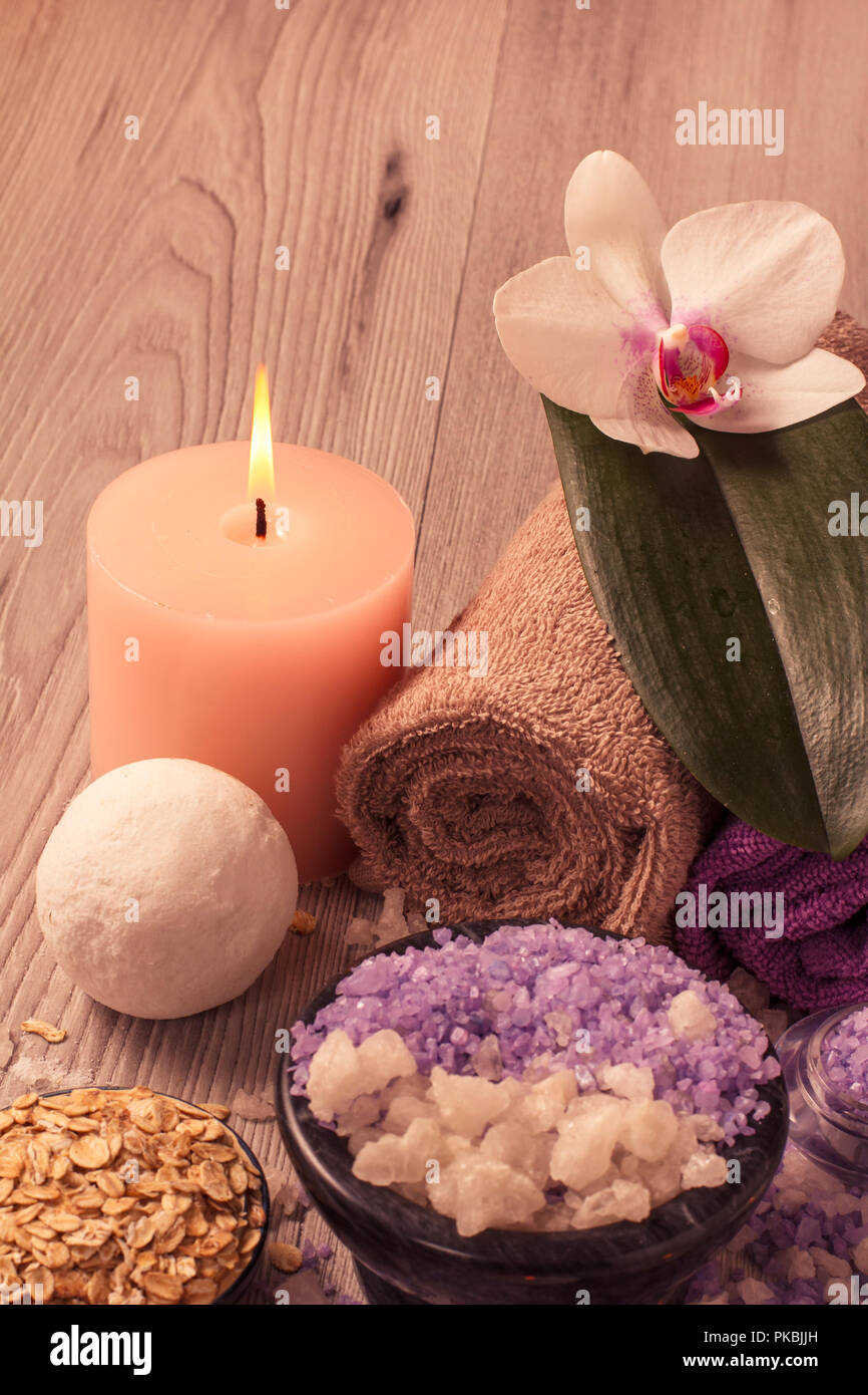 Impostazione di Spa con fiori di orchidea, ciotola con sale marino, scrub,  candela e asciugamani su pannello di legno Foto stock - Alamy